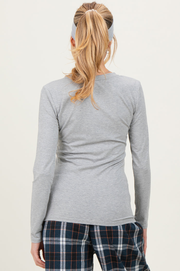 woman wearing a gray long sleeve maternity top, seen from the back, paired with plaid pajamas