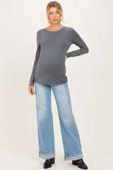 woman wearing a dark gray long sleeve maternity top and light blue wide-leg jeans with a visible baby bump