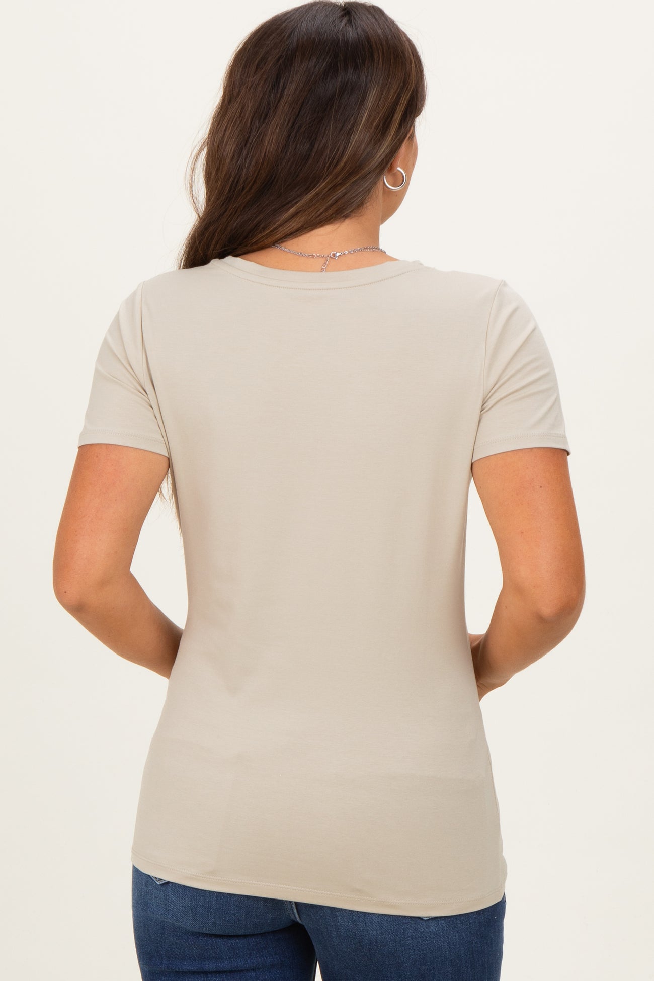 woman wearing a light beige short sleeve maternity top, view from the back