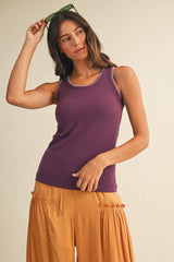 woman wearing a purple sleeveless top with contrasting trim and high-waisted mustard yellow wide-leg pants