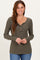 woman wearing an olive green ribbed long sleeve henley top with buttons, smiling and posing with hands on her hips