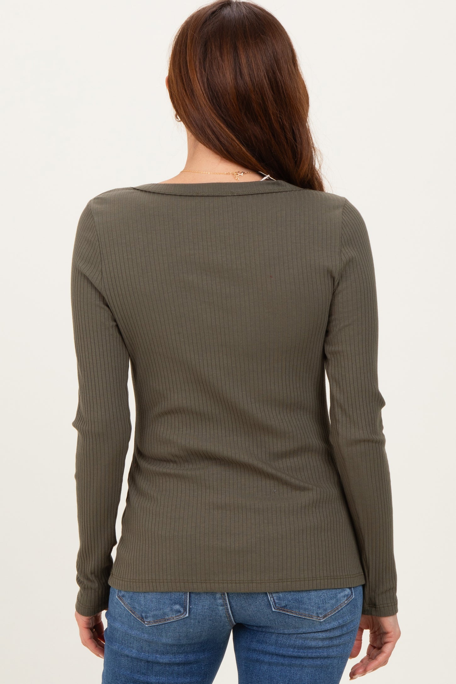 woman wearing an olive green ribbed long sleeve top, seen from the back, paired with blue jeans