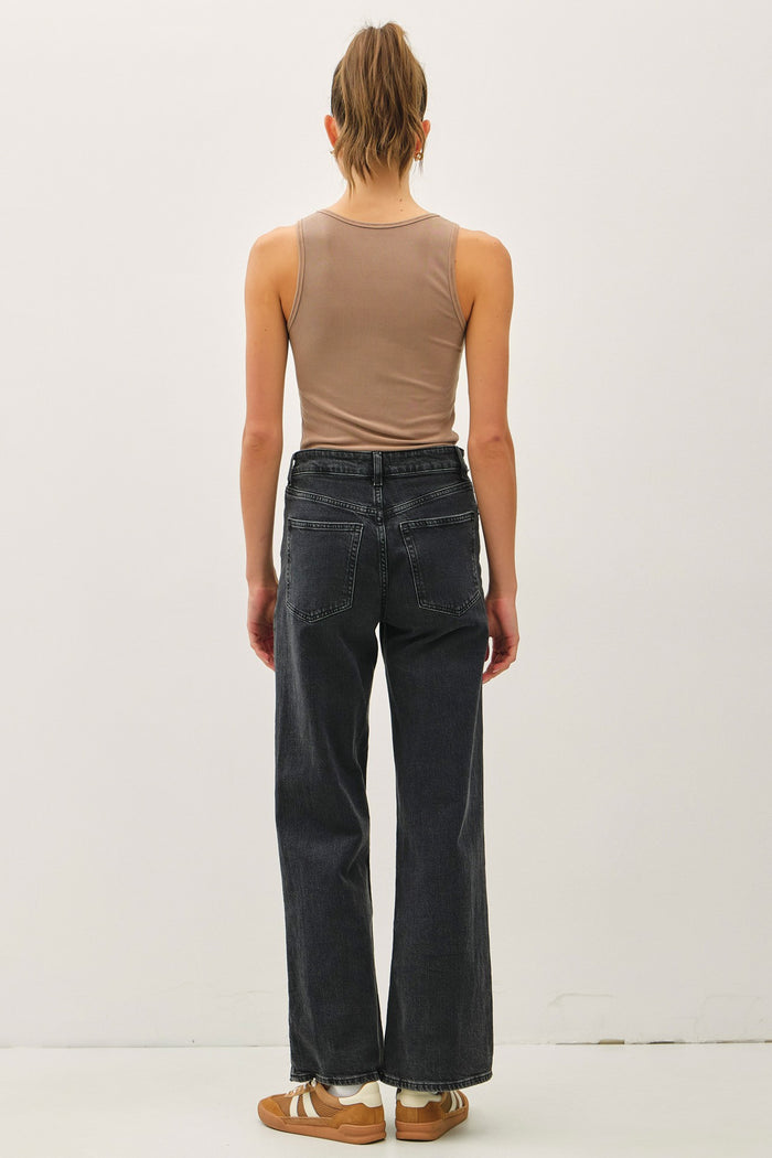 woman wearing a beige tank top and black wide-leg jeans, viewed from the back