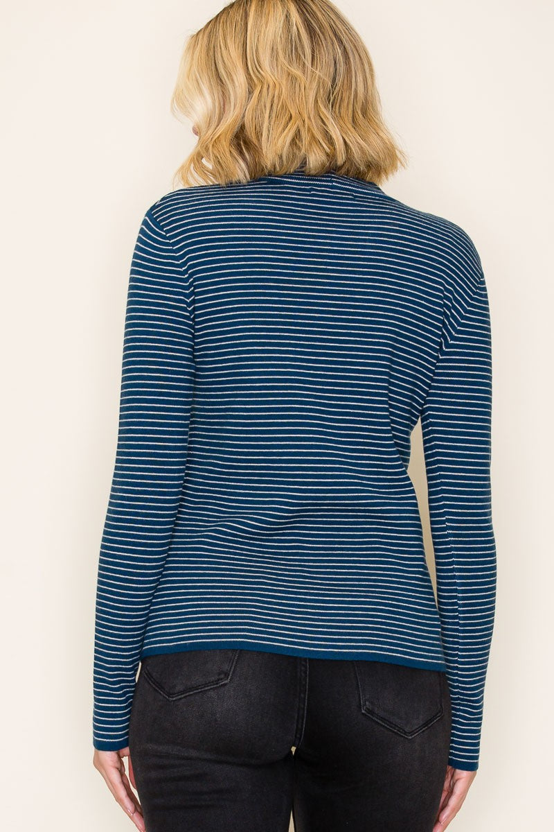 woman wearing a dark teal and white striped long sleeve top, viewed from the back, paired with black jeans