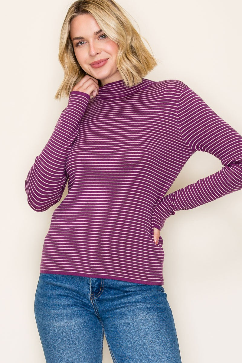 woman wearing a purple and white striped long sleeve turtleneck sweater with fitted sleeves and a relaxed fit