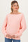 woman wearing a light pink oversized maternity sweater and holding her baby bump