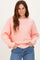 woman wearing a soft pink oversized ribbed knit sweater and blue jeans