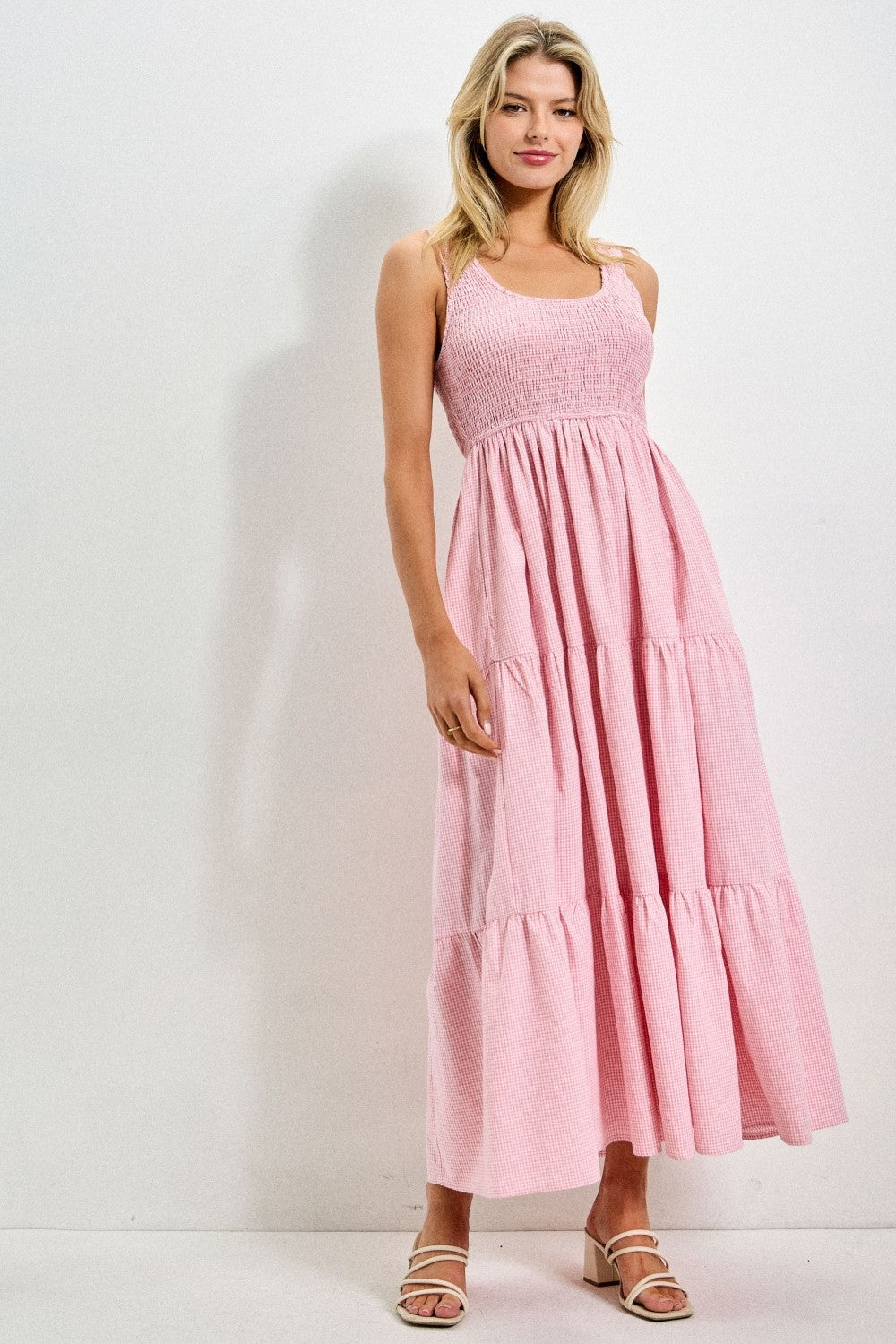 woman wearing a pink smocked tiered maxi dress with spaghetti straps and a flowy silhouette