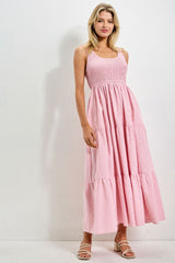 woman wearing a pink smocked tiered maxi dress with spaghetti straps and a flowy silhouette