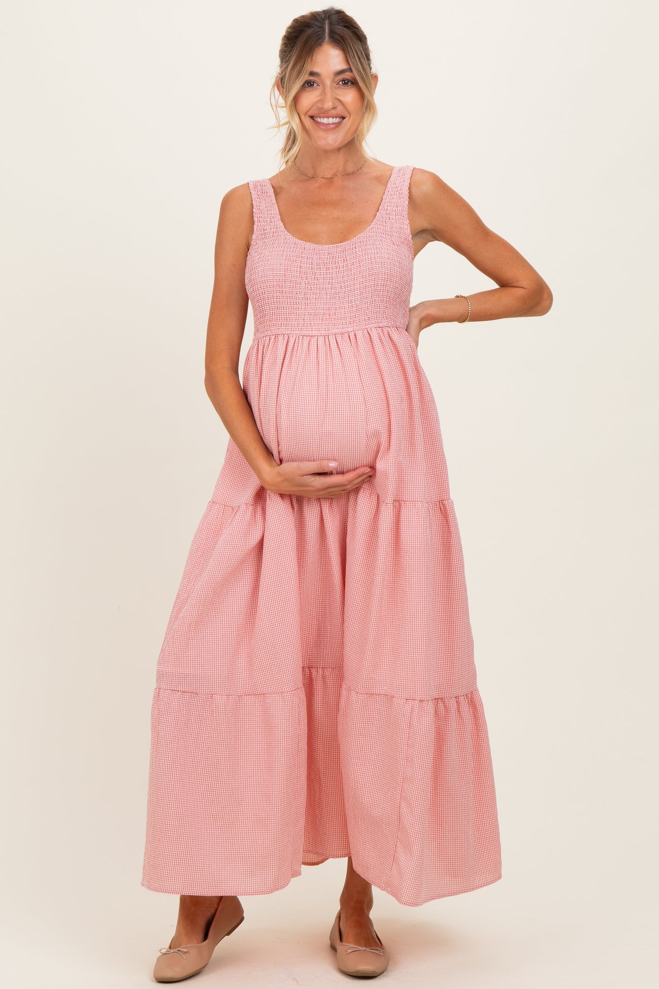 woman wearing a pink striped maternity maxi dress and holding her baby bump