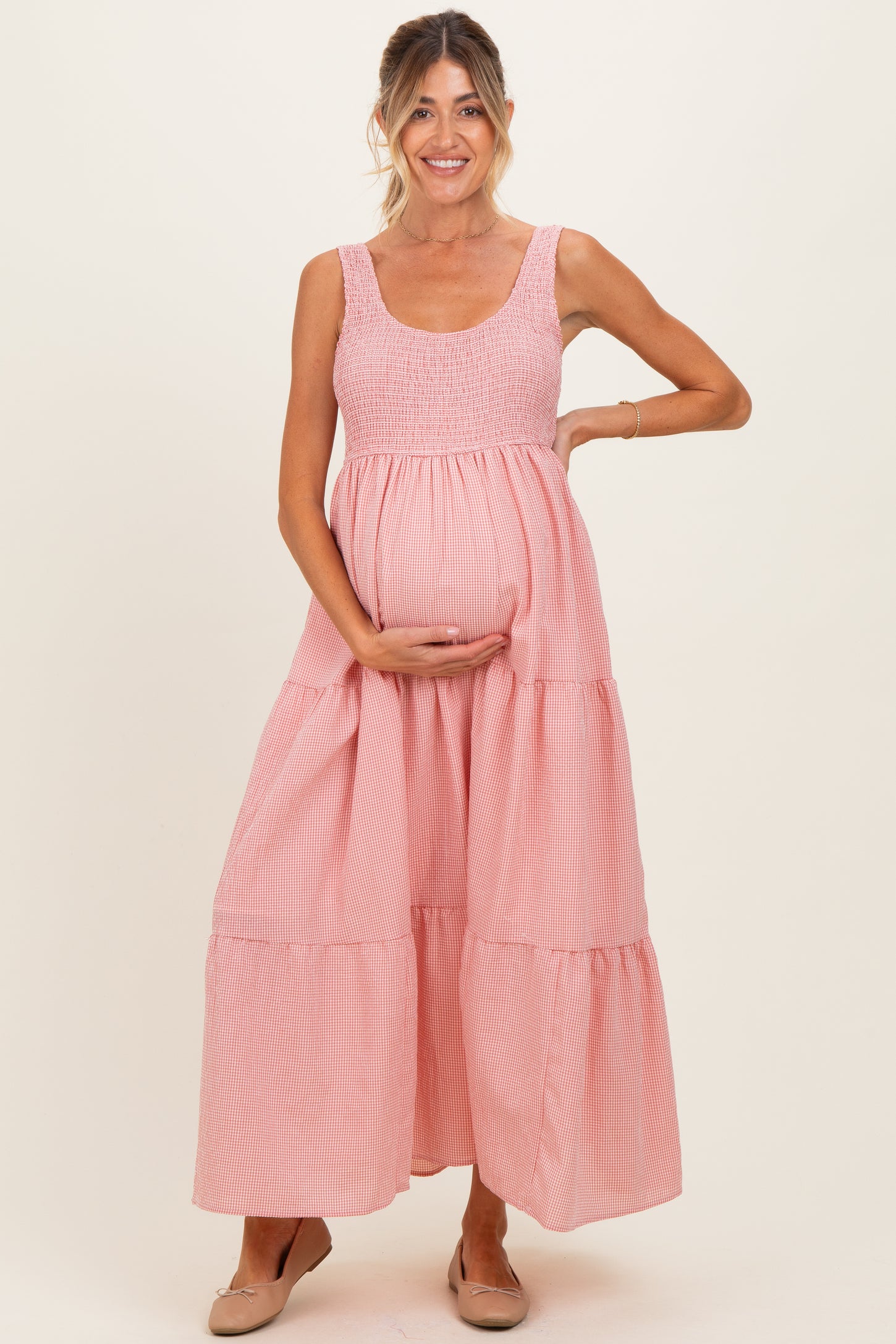 woman wearing a pink striped maternity maxi dress and holding her baby bump