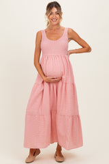 woman wearing a pink striped maternity maxi dress and holding her baby bump