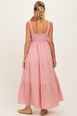 woman wearing a pink striped maternity maxi dress with a smocked bodice and tiered skirt, seen from the back