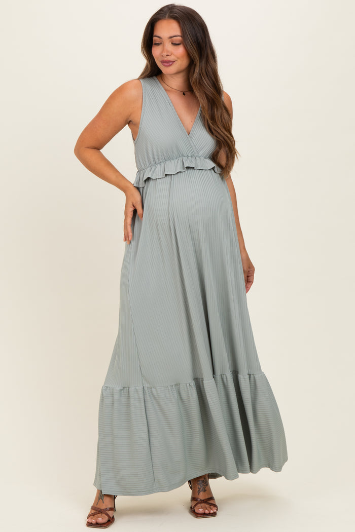 woman wearing a light green striped maternity maxi dress with a ruffled neckline and flared hem, showcasing her baby bump