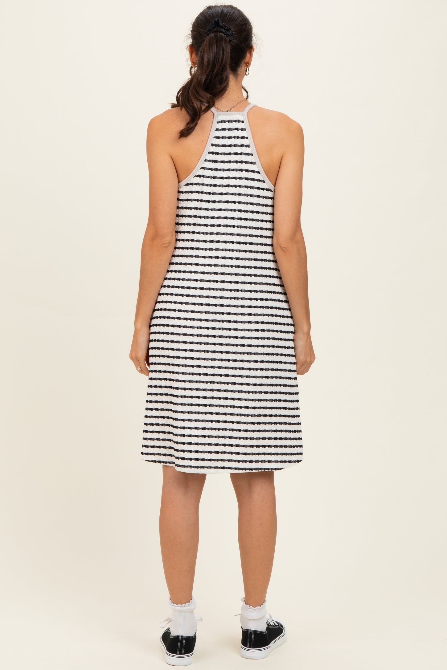 woman wearing a black and white striped halter dress, showing the back view with a relaxed fit and casual style