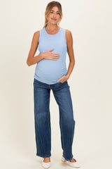 woman wearing a light blue ribbed maternity tank top and blue wide-leg jeans, holding her baby bump
