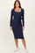 woman wearing a navy long sleeve midi dress with a square neckline and a tie belt, paired with white sneakers