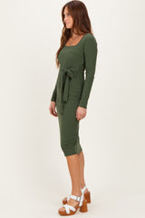 woman wearing a dark green ribbed midi dress with long sleeves and a tie waist detail