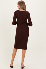 woman wearing a brown long sleeve maternity dress, seen from the back, fitted style with a midi length