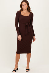 woman wearing a brown long sleeve dress with a square neckline and tie waist detail