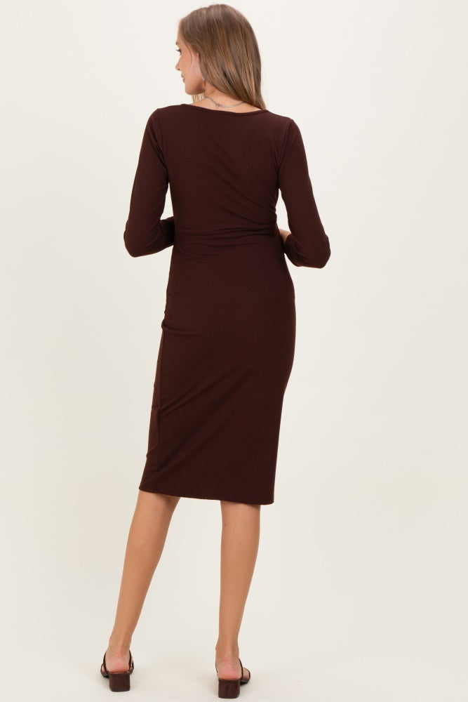 woman wearing a brown long sleeve maternity dress, seen from the back, fitted style with a midi length