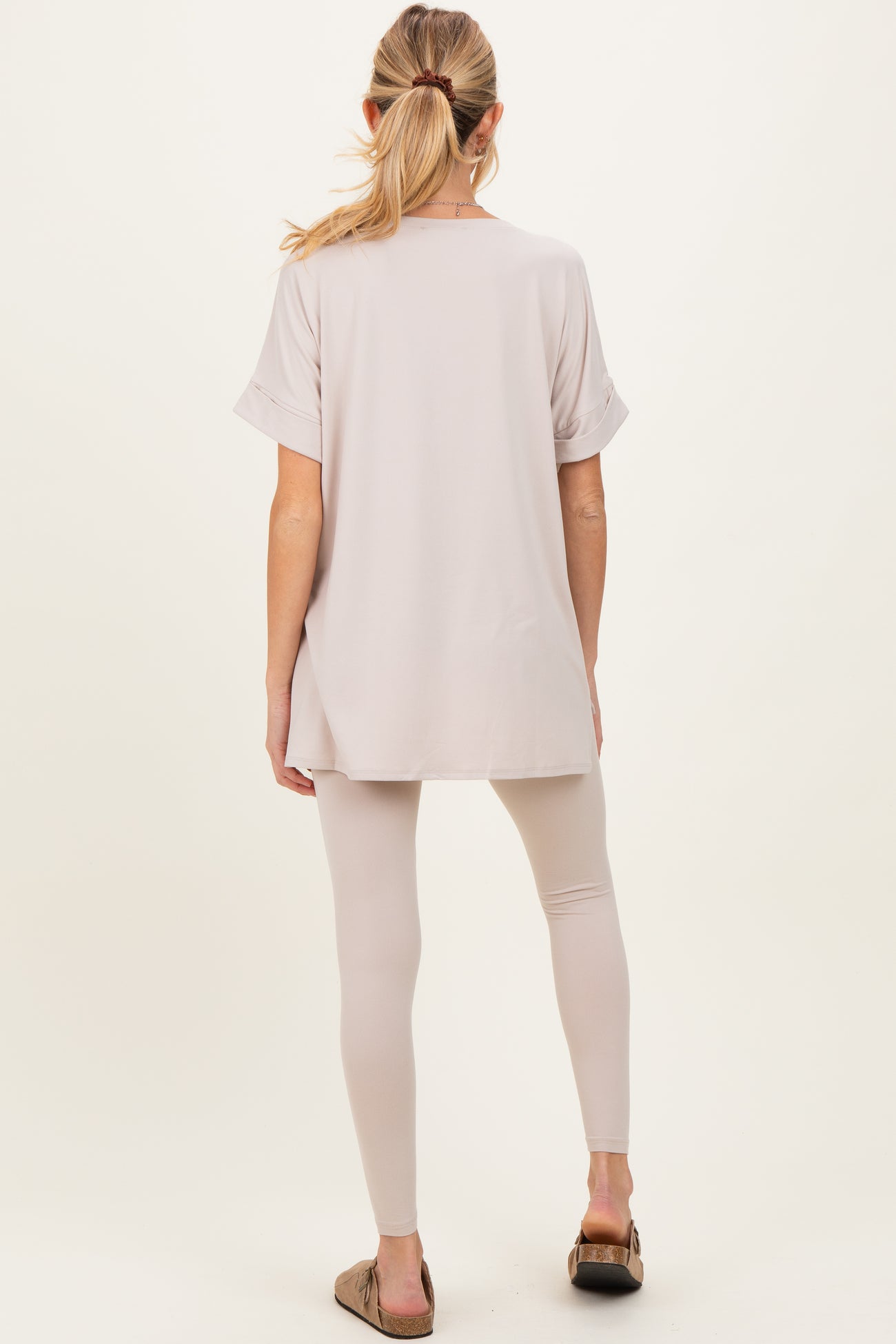 woman wearing a light beige maternity top and matching leggings, showing a relaxed fit and loose silhouette