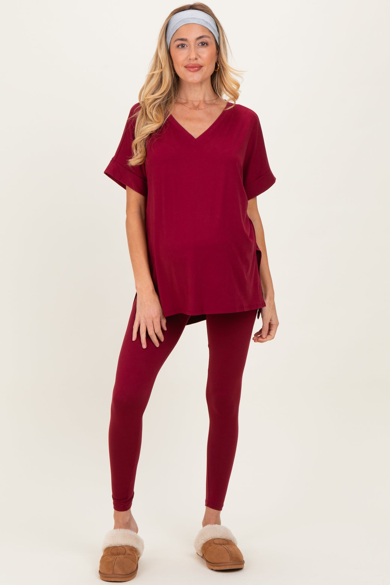 woman wearing a burgundy maternity top and matching leggings, styled with a headband and cozy slippers, baby bump visible