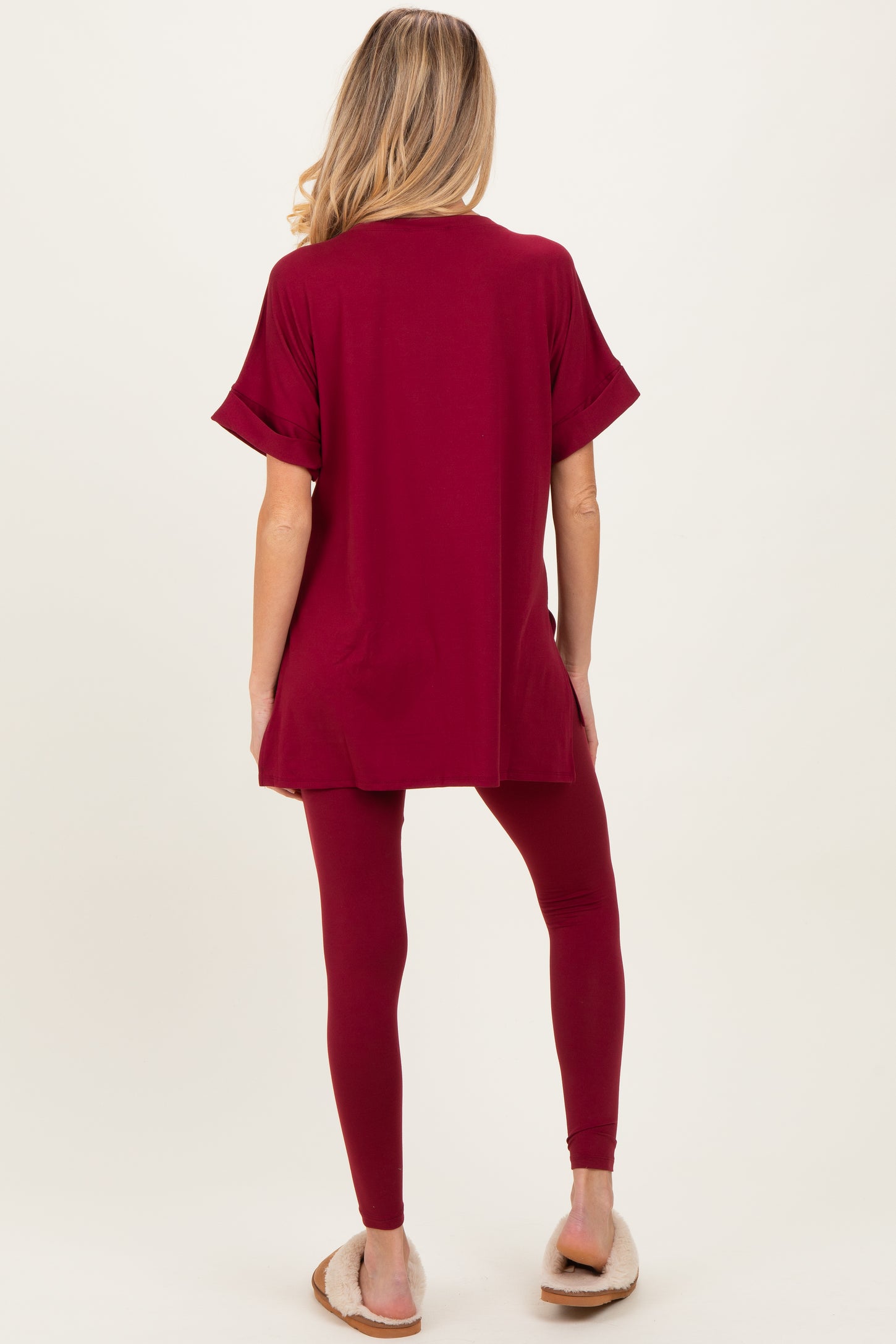 woman wearing a burgundy maternity top with rolled sleeves and matching leggings, showing a baby bump from behind