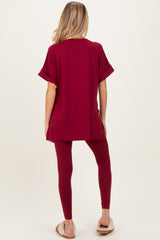 woman wearing a burgundy maternity top with rolled sleeves and matching leggings, showing a baby bump from behind