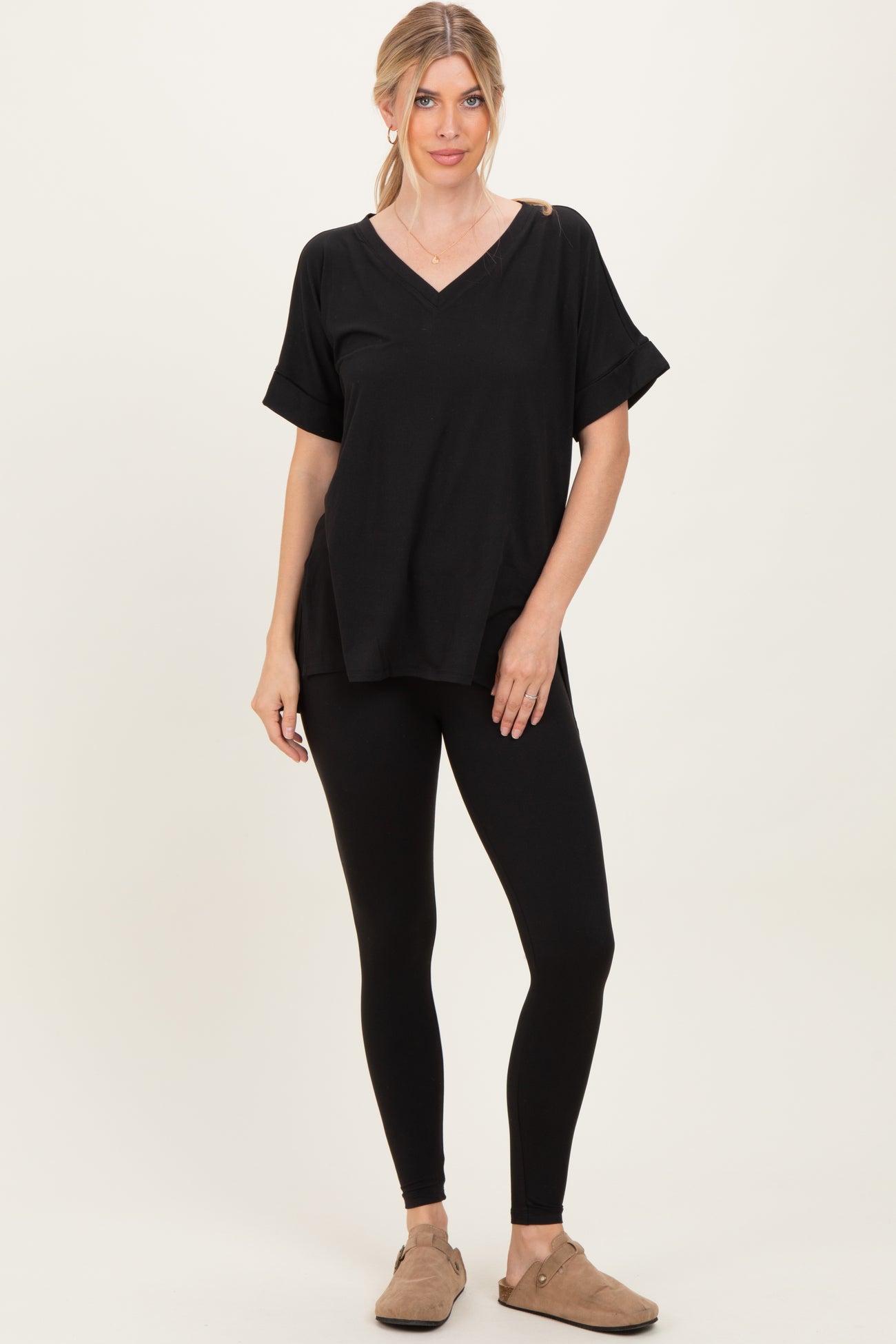 woman wearing a black v-neck oversized top with a shoulder cutout and black leggings