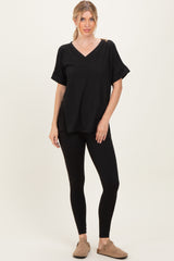 woman wearing a black v-neck oversized top with a shoulder cutout and black leggings