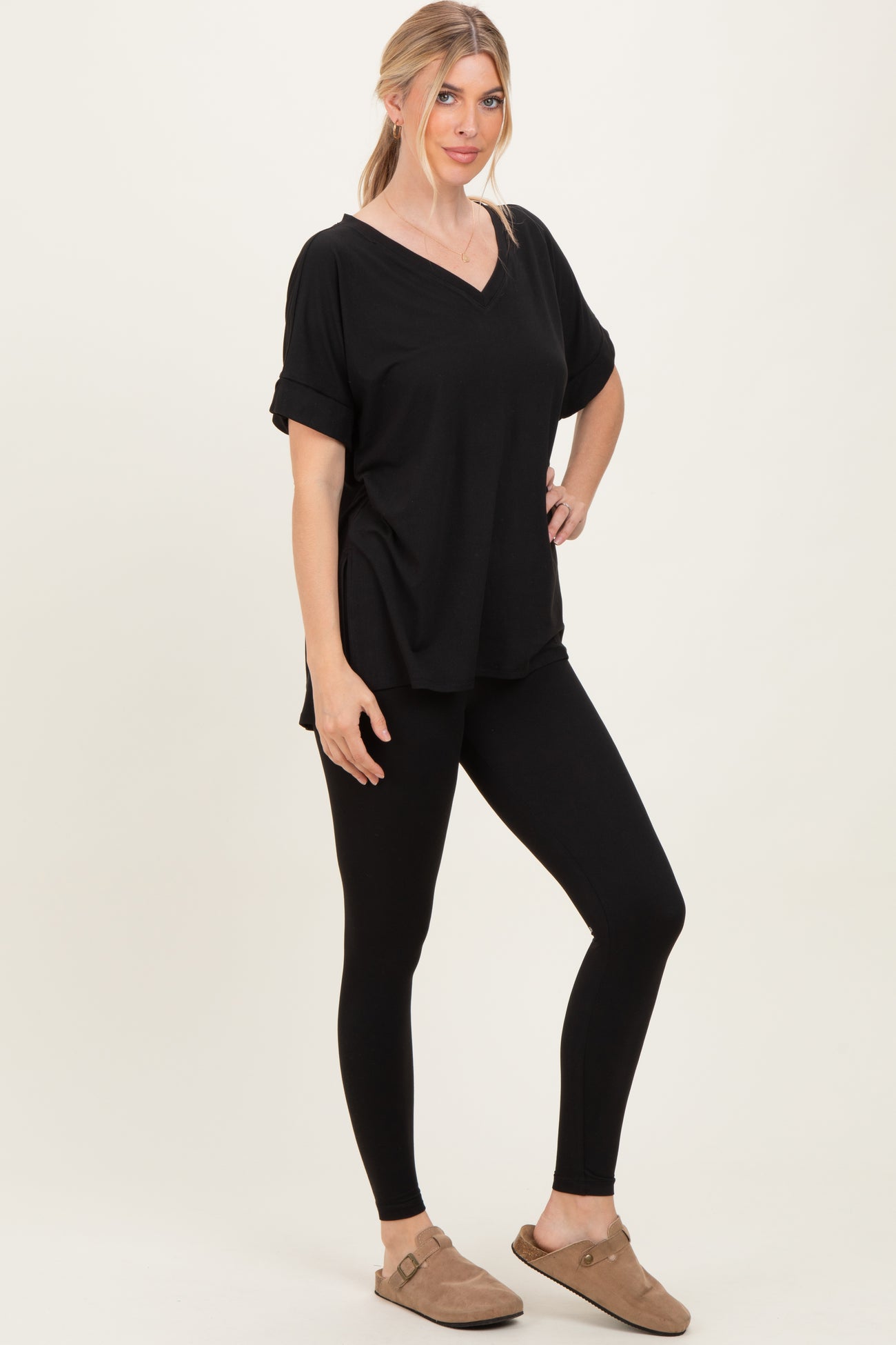 woman wearing a black short sleeve v-neck top and black leggings with tan slip-on shoes