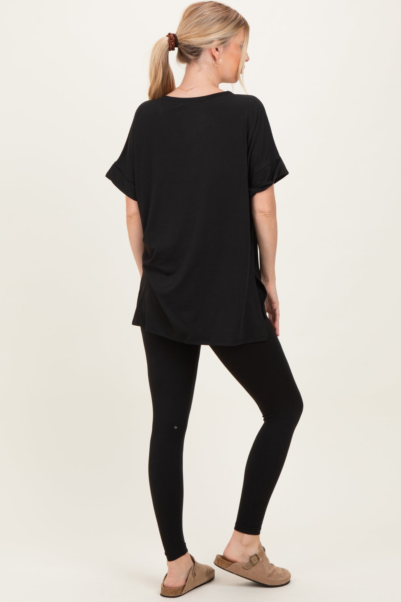 woman wearing a black oversized t-shirt and black leggings, posed from the back
