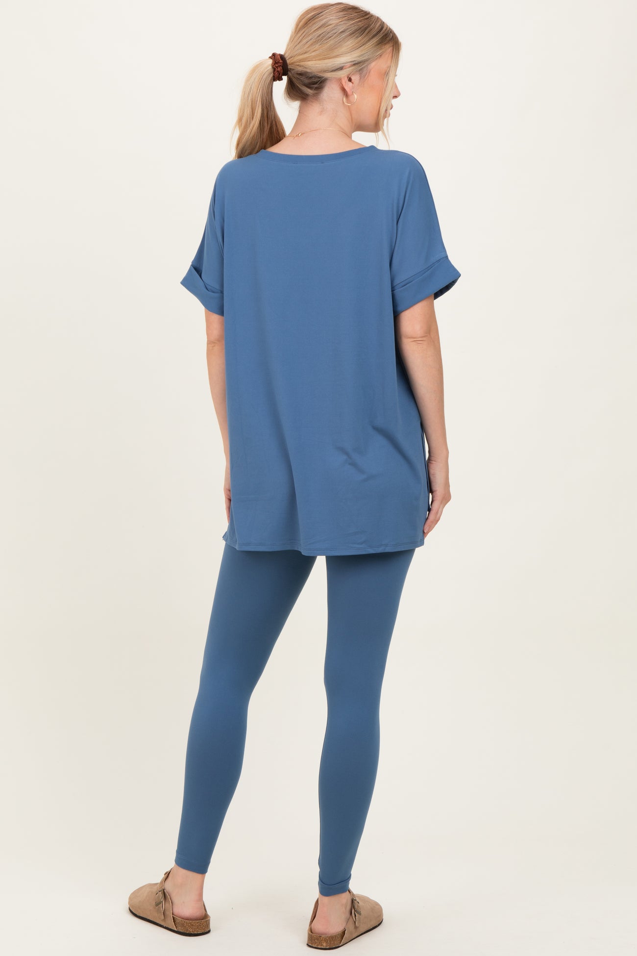 woman wearing a blue oversized top with rolled sleeves and matching blue leggings, seen from the back