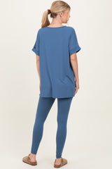 woman wearing a blue oversized top with rolled sleeves and matching blue leggings, seen from the back