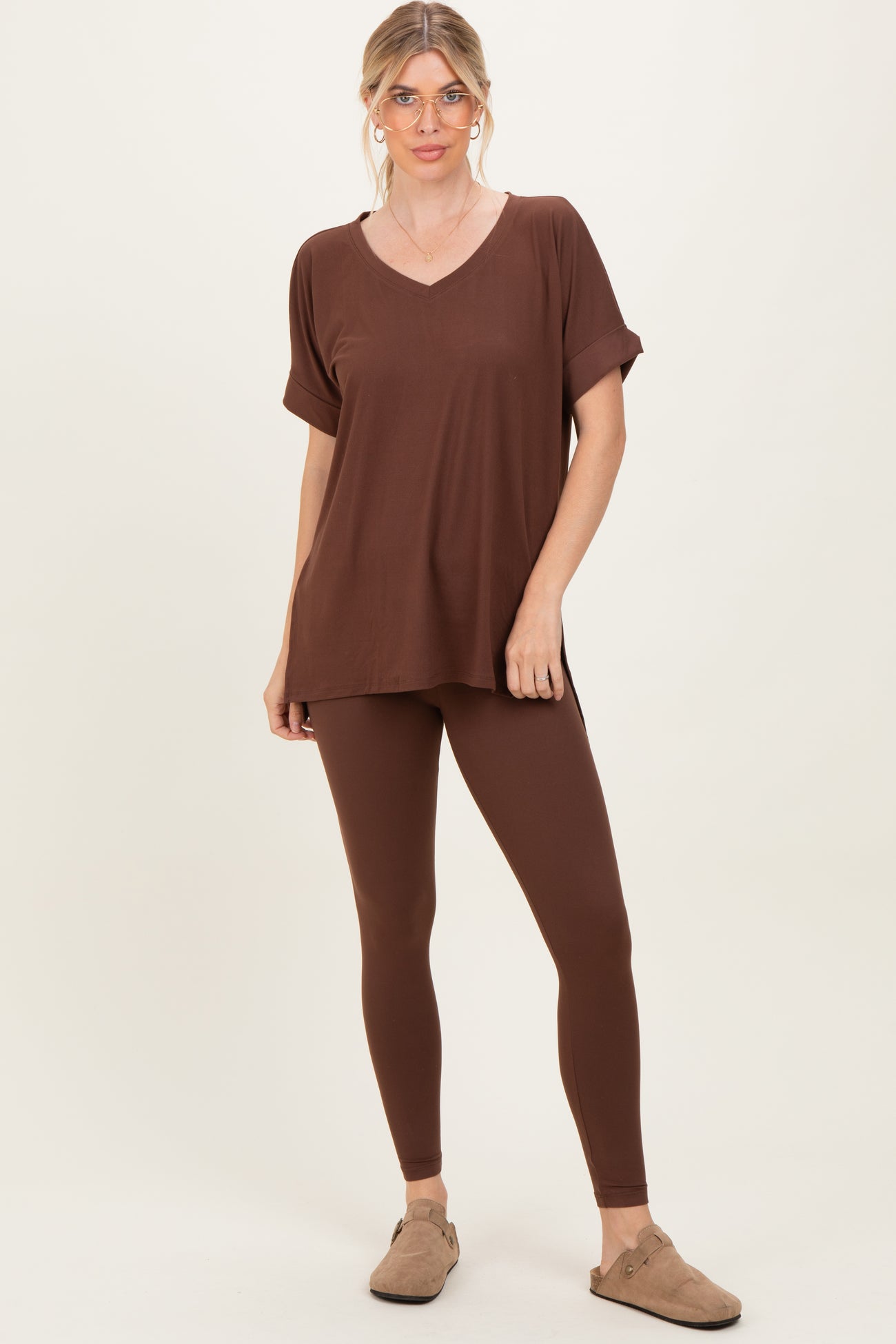 woman wearing a brown v-neck oversized top and matching brown leggings, standing with a relaxed pose
