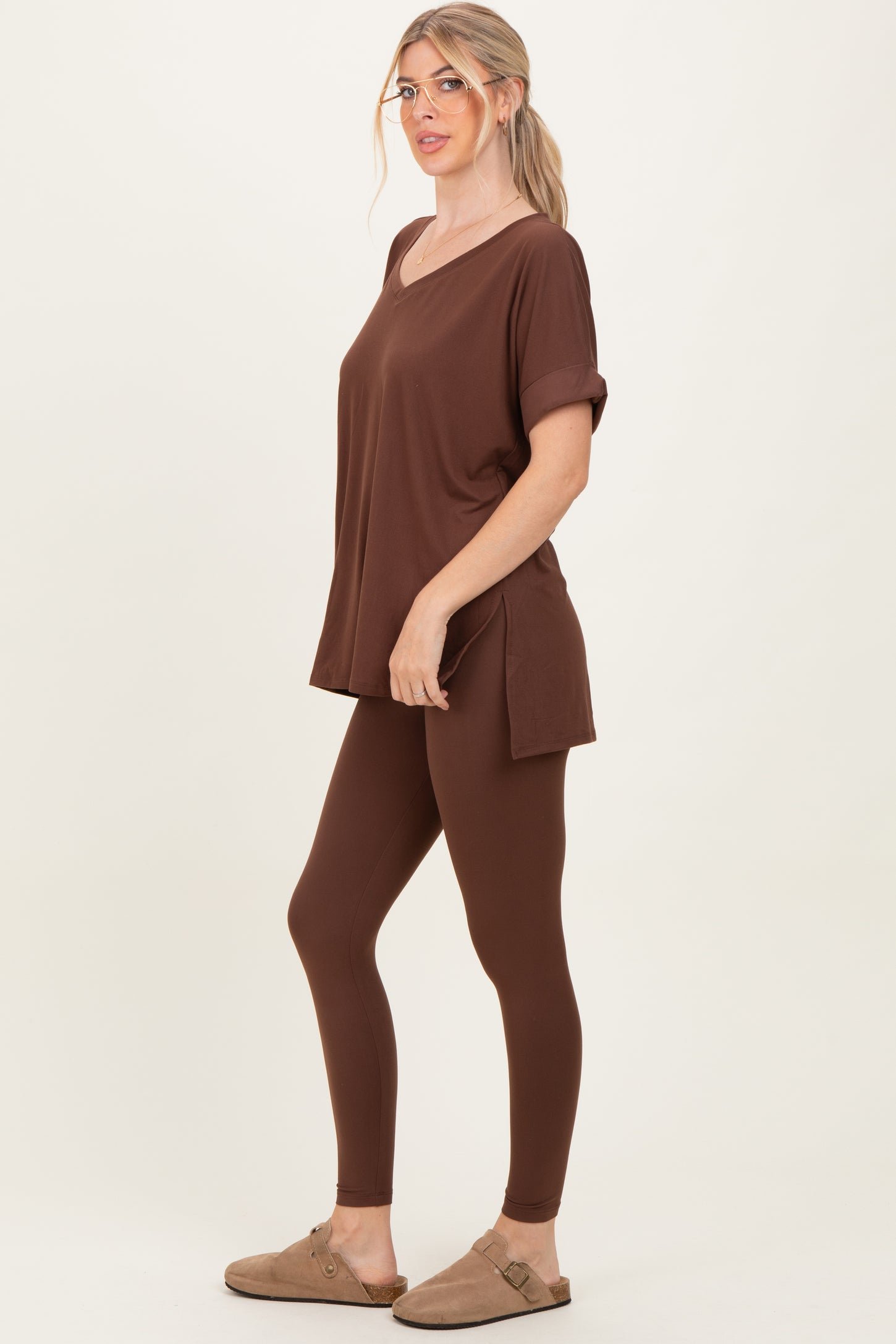 woman wearing a brown oversized v-neck t-shirt and matching leggings with side slits, paired with brown slip-on shoes