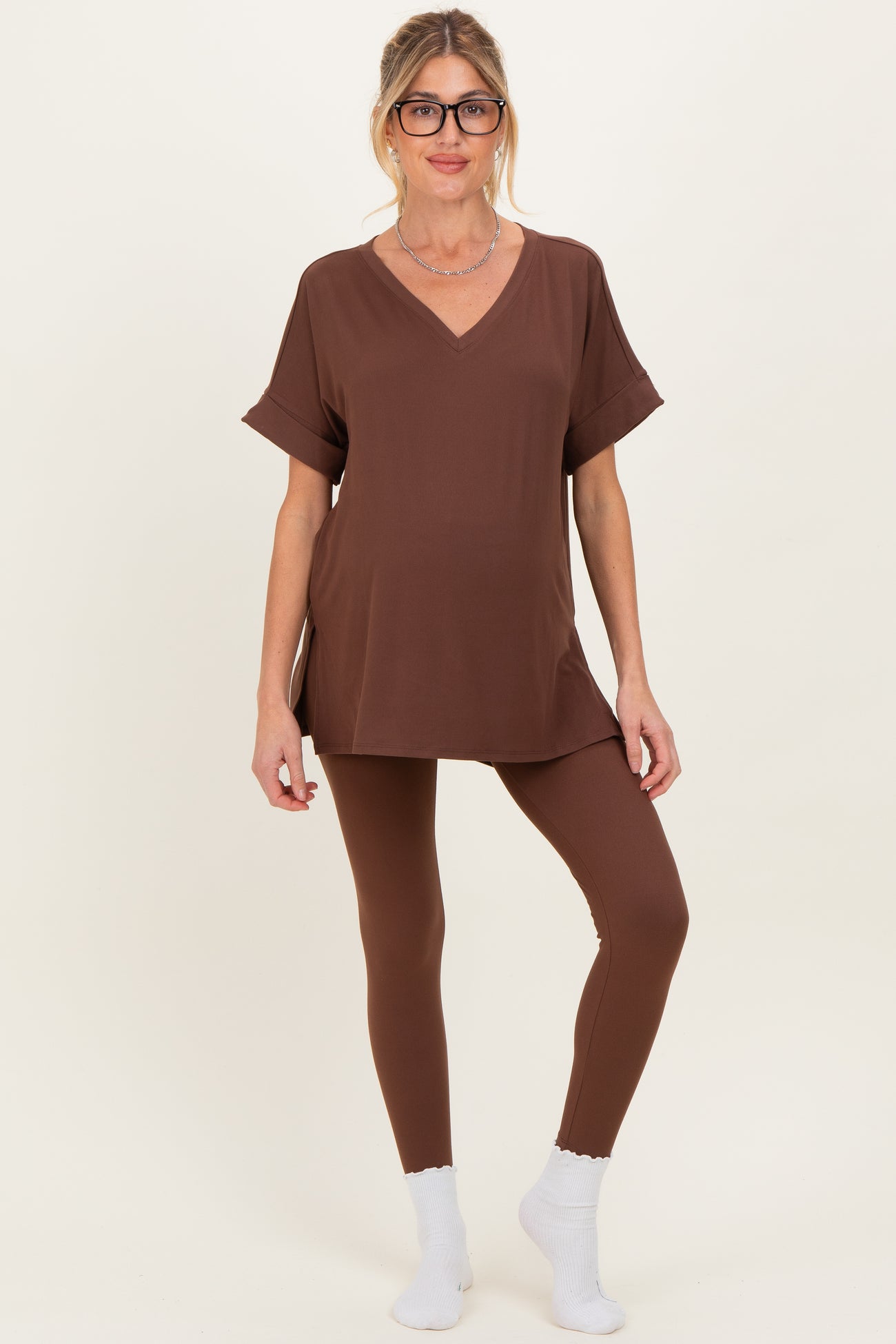 woman wearing a brown v-neck maternity top and matching leggings with a baby bump visible
