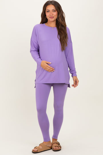woman wearing a purple long sleeve maternity top and matching leggings, holding her baby bump