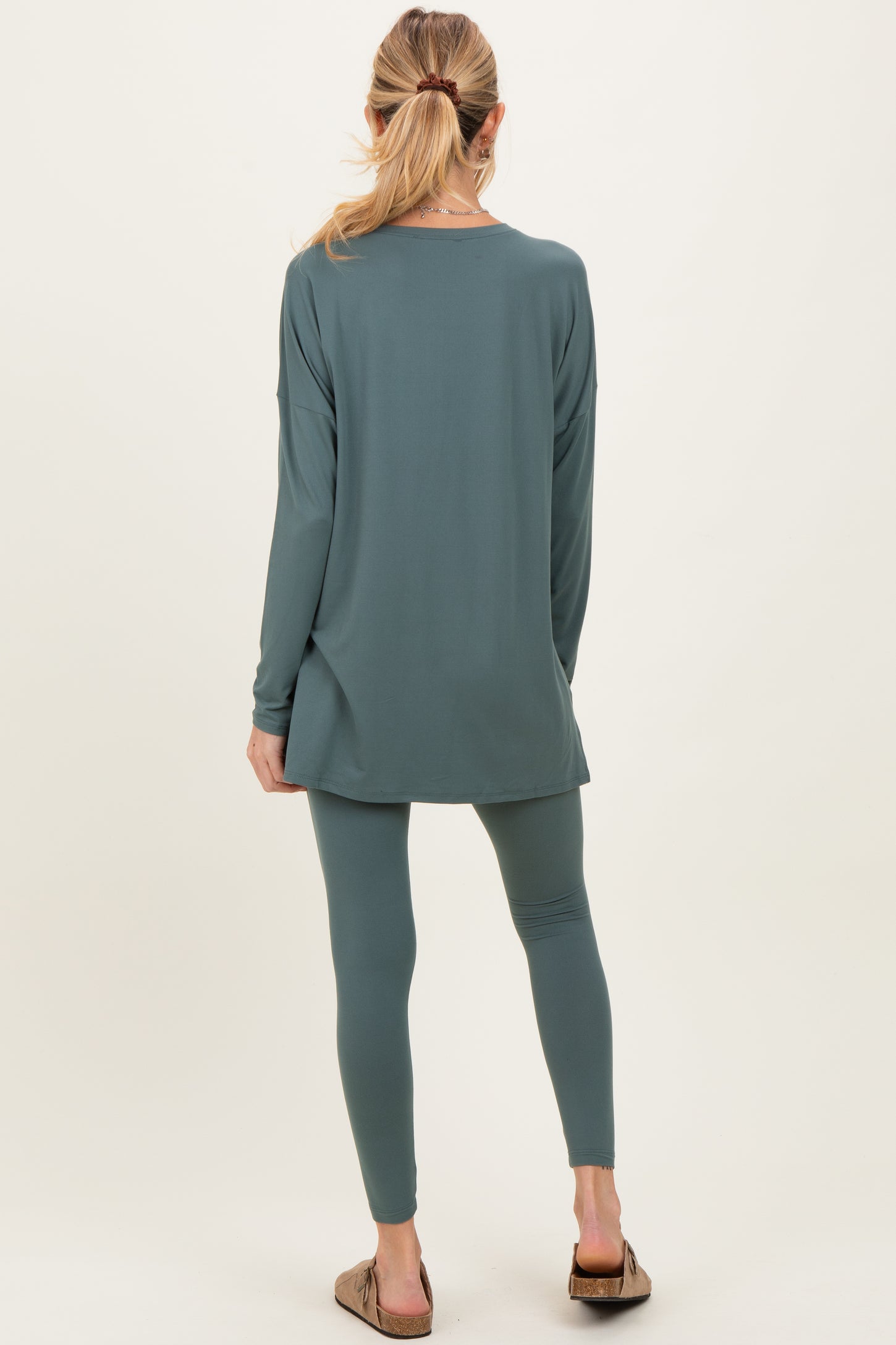 woman wearing a long sleeve green maternity tunic top and matching leggings, seen from the back