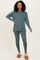 woman wearing a teal long sleeve top and matching leggings, styled with cozy slippers