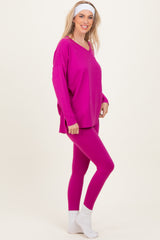 woman wearing a bright pink oversized v-neck top and matching pink leggings, styled with white ankle socks and a headband