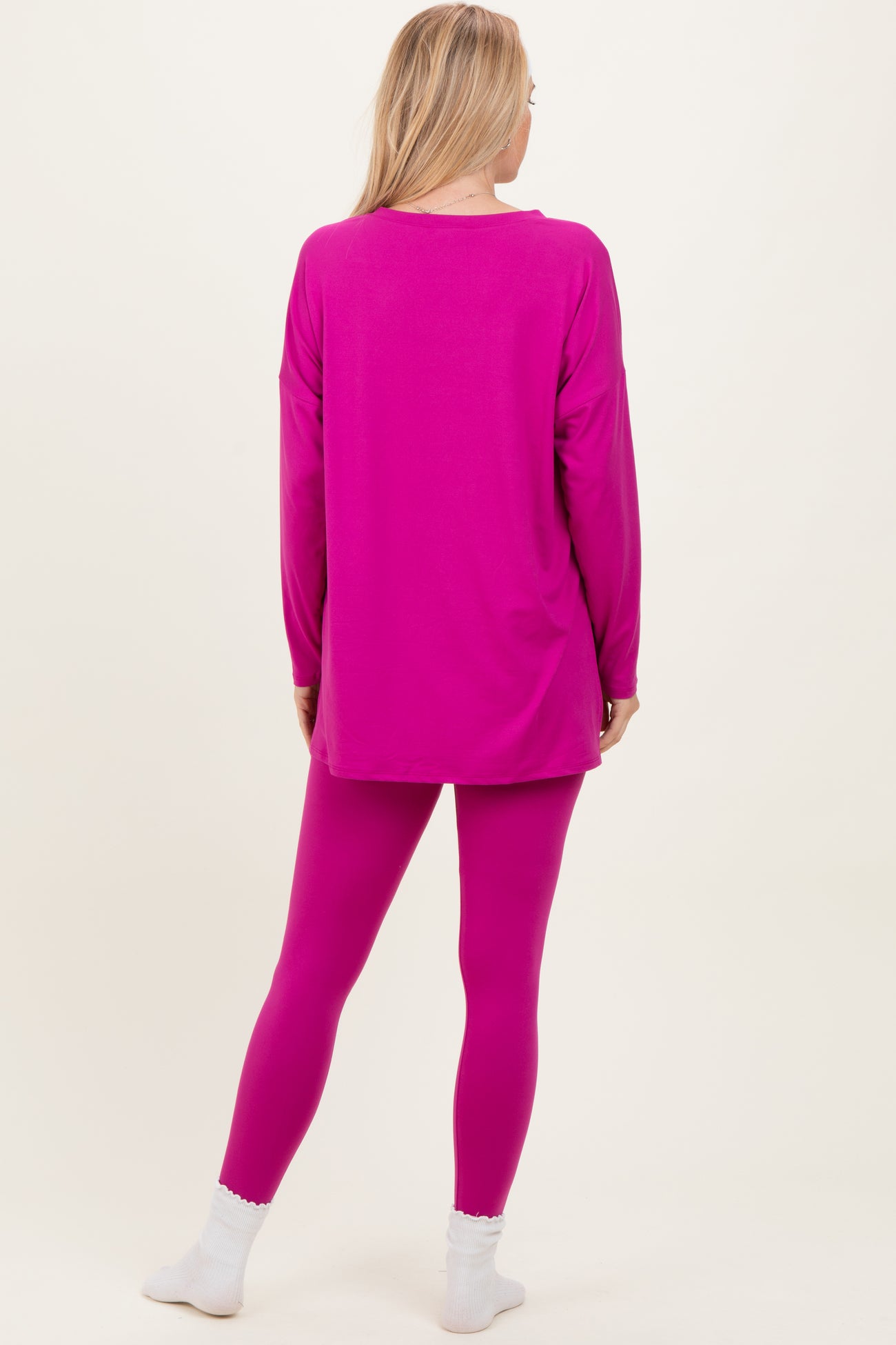 woman wearing a bright pink long sleeve top and matching leggings, seen from the back