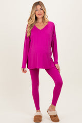 woman wearing a hot pink maternity top and matching leggings, with a visible baby bump, styled with cozy slippers