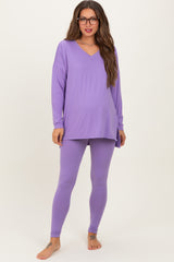 woman wearing a purple maternity loungewear set with a long sleeve top and leggings, showing her baby bump