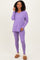 woman wearing a purple long sleeve v-neck top and matching leggings, paired with cozy slippers