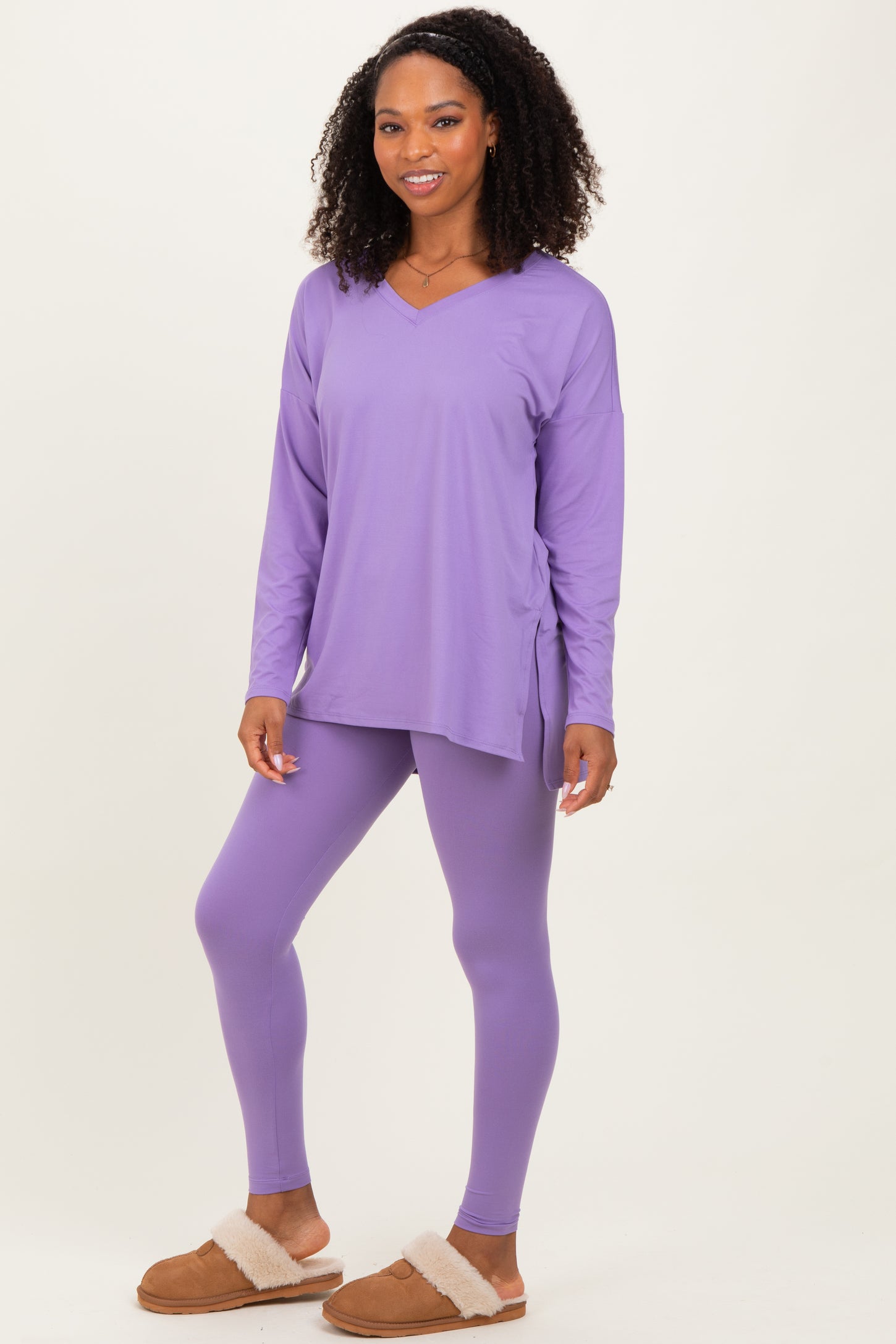 woman wearing a purple long sleeve top with side slits and matching purple leggings, styled with cozy slippers