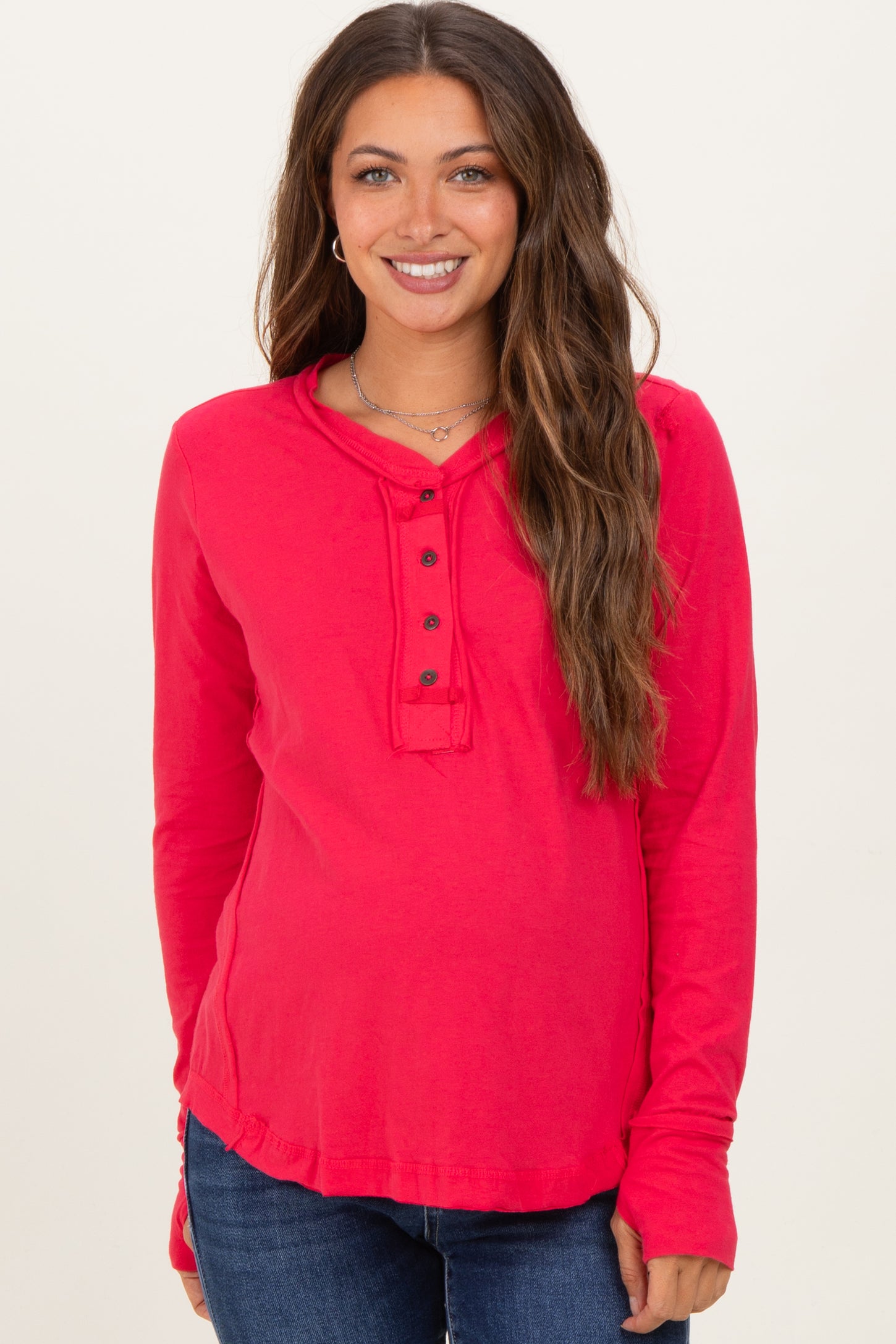 woman wearing a red long sleeve maternity top with button details and a visible baby bump