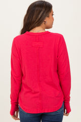 woman wearing a bright pink maternity long sleeve top showing a unique back design and casual fit