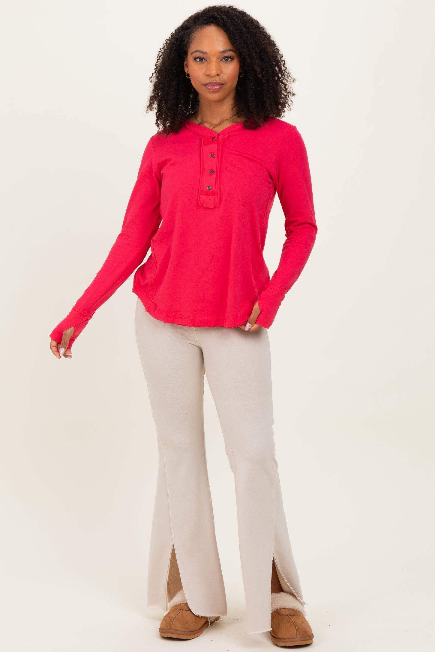 woman wearing a bright pink long sleeve henley top and beige flared pants